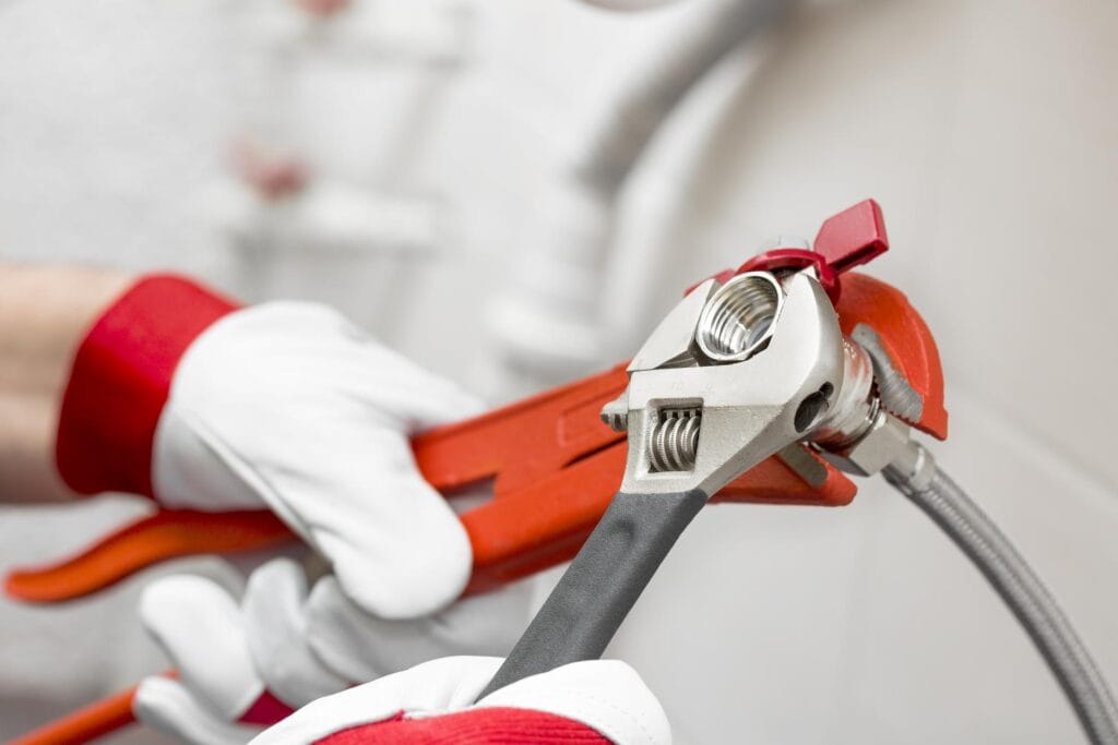 Plumber holding pipe wrenches for an emergency repair in Canton