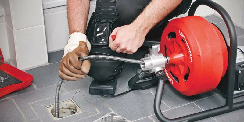 Plumber using a drain-cleaning machine in Canton