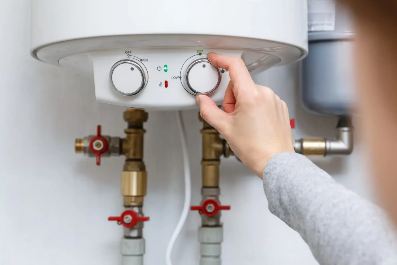Homeowner adjusting the temperature controls on a water heater in Canton